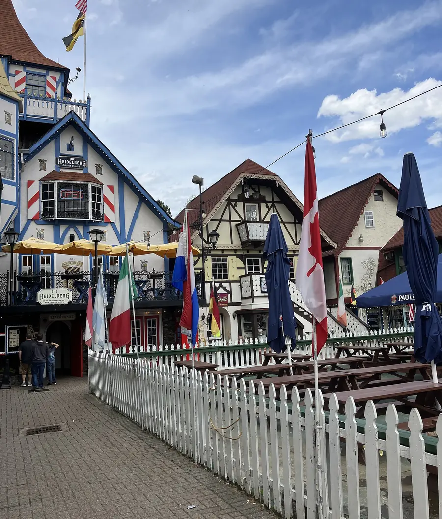 Painted Bavarian-style facades in Helen with flags of several countries flying above a white picket fence.